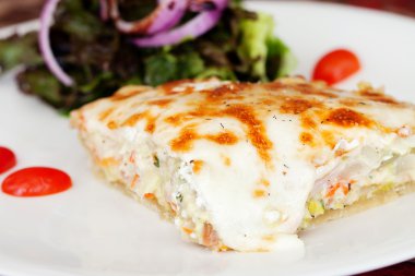 pırasa ve keçi bir dilim peynirli gevrek yaprak salata ve domates ile bir tabakta kiş