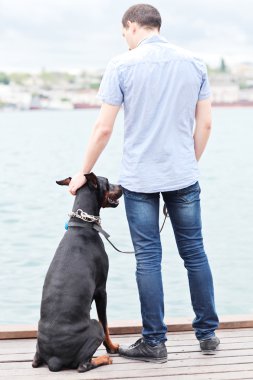 bir adam ve okyanusa bakan bir oturma köpek.