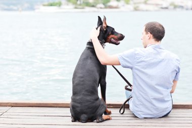bir adam ve okyanusa bakan bir oturma köpek.