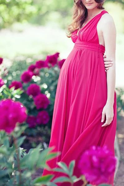 Zwangere vrouw in bloeiende tuin van peony — Stockfoto