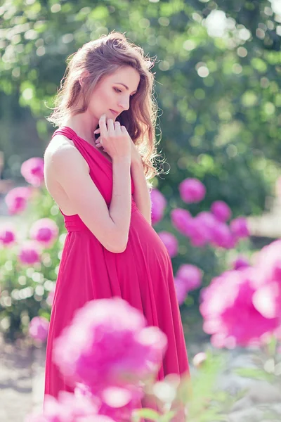 Zwangere vrouw in bloeiende tuin van peony — Stockfoto