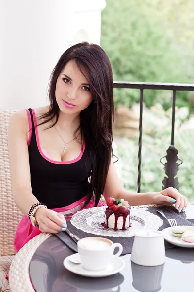 Jonge mooie vrouw eten een dessert en drankje cappuccino café met mooi uitzicht — Stockfoto