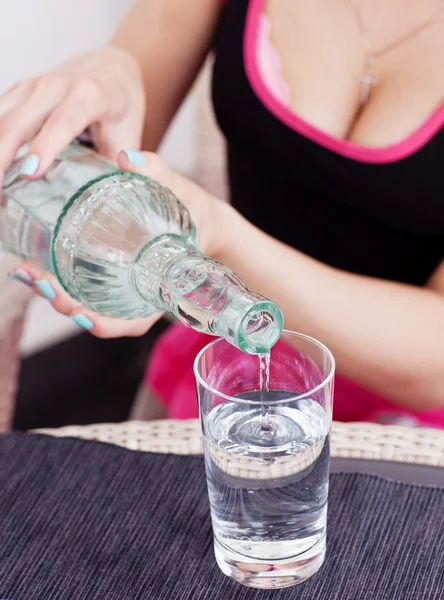 Agua vertida de botella a vidrio por mujer en vestido rosa — Foto de Stock