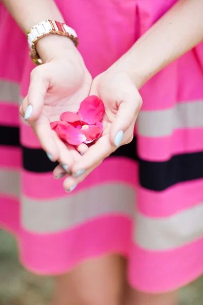 Hand van een vrouw vol met rozenblaadjes klaar om te gooien, concentreren op bloemblaadjes — Stockfoto