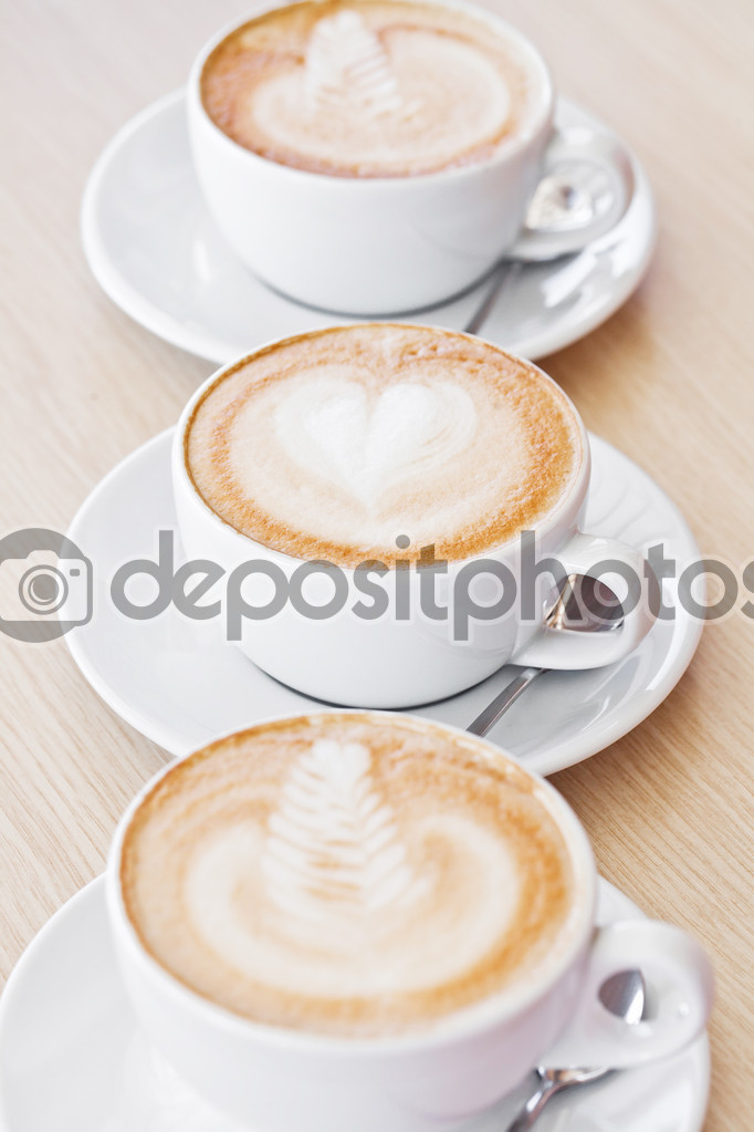 Three white cups of assorted coffee on table