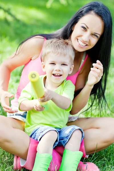 Genç anne ve küçük oğlunu açık havada renkli lastik çizme — Stok fotoğraf
