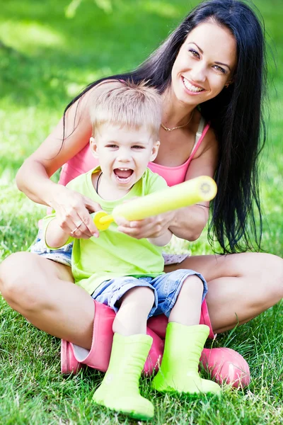 Joven madre y su pequeño hijo al aire libre en botas de goma de colores — Foto de Stock