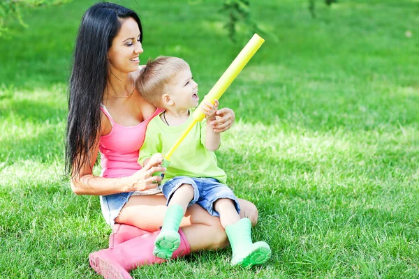 Genç anne ve küçük oğlunu açık havada renkli lastik çizme — Stok fotoğraf