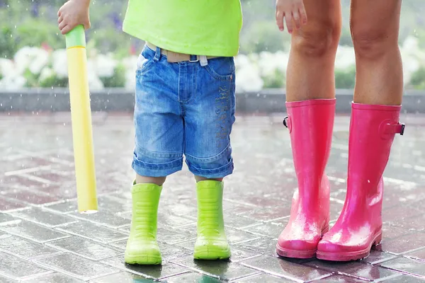 Child and mother wearing pink and green rain boots