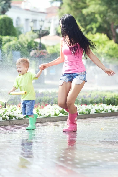 Speelse jongen en zijn moeder runing op regenachtige zomerdag — Stockfoto