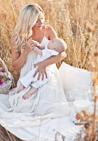 Счастливая семья на закате. Мать в белом платье с ребенком в природе — стоковое фото
