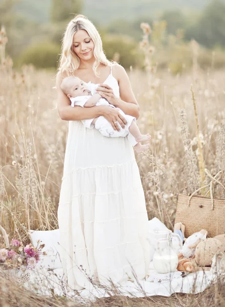 Счастливая семья на закате. Мать в белом платье с ребенком в природе — стоковое фото