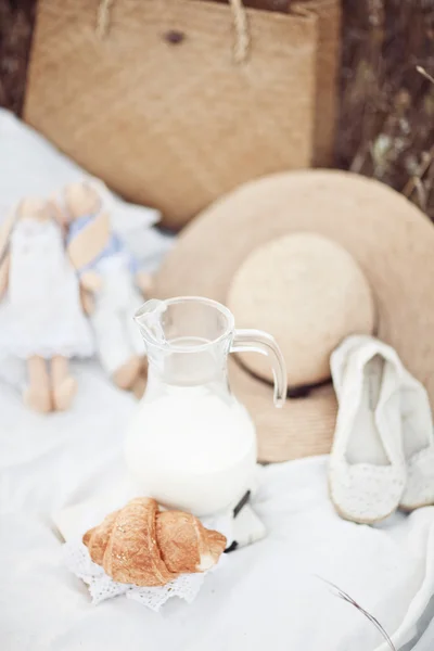 Picknick-Detail: Hut, Milch, Tilda, Croissant, Schuhe auf weißem Stoff in der Natur — Stockfoto