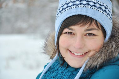 Mavi paltolu açık havada gülümseyen genç kadın