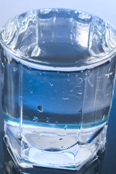 Vaso con agua sobre fondo brillante — Foto de Stock