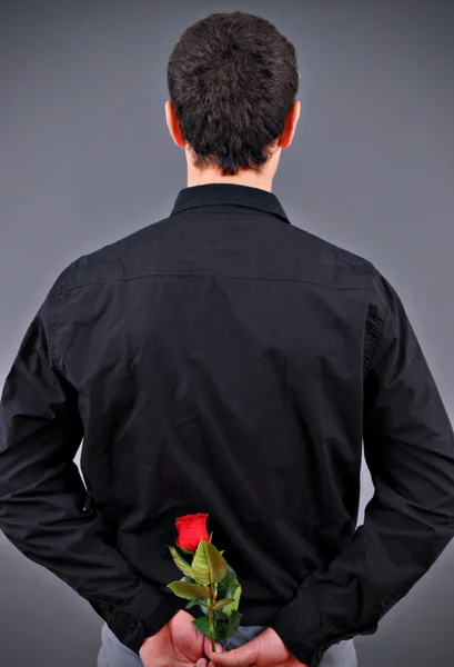 Hombre escondiendo una flor detrás de su espalda — Foto de Stock