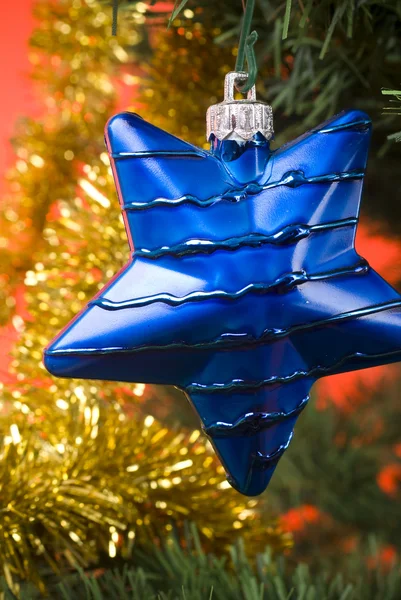 Blue star hanging from christmas tree — Stock Photo, Image