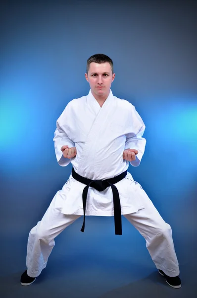 Young sporty karate man doing special exercise on gray background — Stock Photo, Image