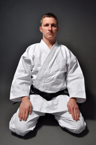 Człowiek karate na strzał studio szary tło — Zdjęcie stockowe