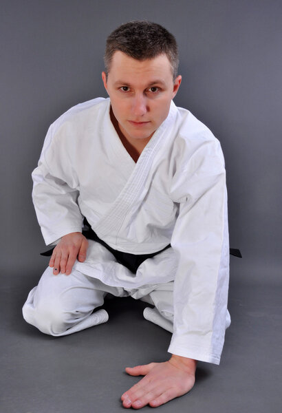 Karate man in relaxation pose, isolated in white