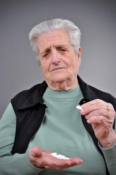 Een senior vrouw met pillen in haar hand — Stockfoto