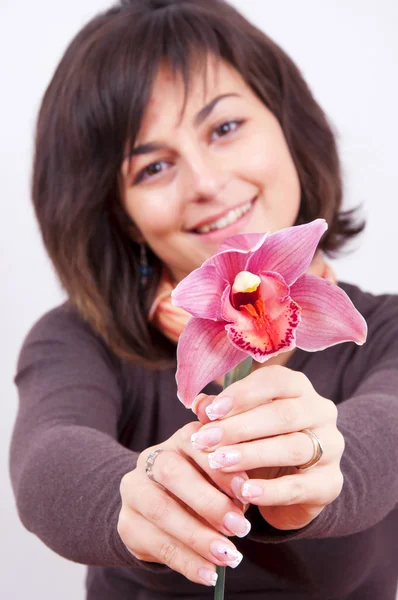Güzel bir orkide çiçek veren gülümseyen kız — Stok fotoğraf