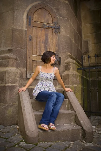 Young beautiful girl sitting front of the door — Stock Photo, Image