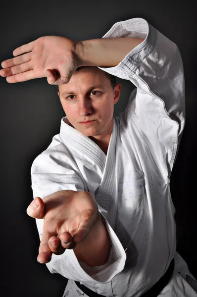 Ung sportig karate man gör speciella övning på grå bakgrund Stockfoto