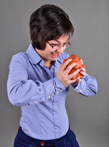 Young woman trying to get money from her piggy bank — Stock Photo, Image