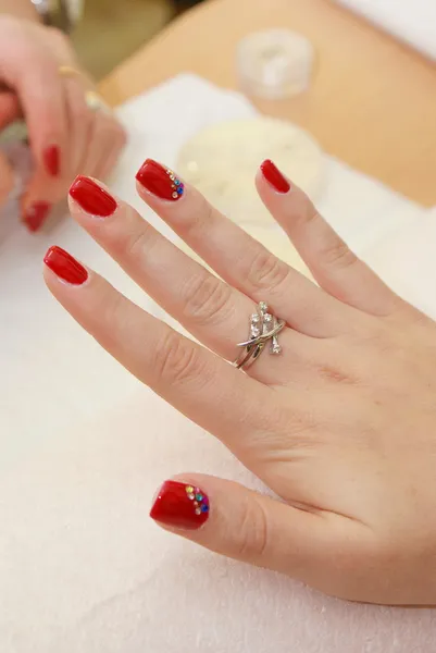 Manikérka použití červený lak na ženské prsty. — Stock fotografie