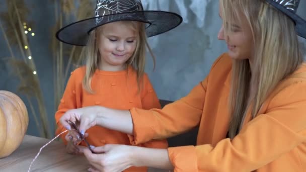 Kvinna och barn gör sig redo för Halloween hemma. Gör en pappersträdgård med dina egna händer. DIY part inredning koncept. Festlig halloweendräkt. — Stockvideo