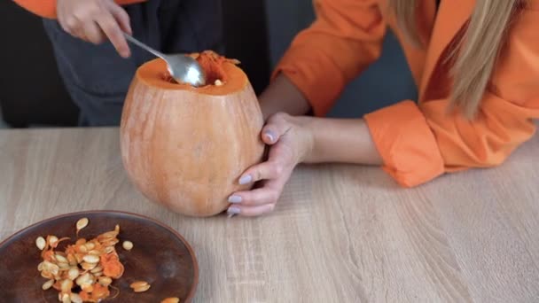 Close-up van een kind hand trekken zaden en vezelmateriaal uit een pompoen voordat ze worden gesneden voor Halloween. Jack-o-lantaarn. het gezin bereidt zich voor op de vakantie. — Stockvideo