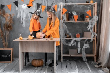 Cadı anne ve kızı Cadılar Bayramı için evde bir balkabağı hazırlıyorlar. Kız tohumları ve portakal hamurunu çıkarıyor. Annesi cadı şapkalı çocuk fenerde Jack 'i canlandırıyor..