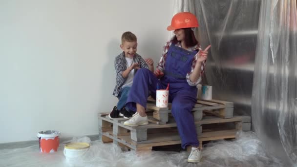 Kavkazská žena a dítě odpočívají a sedí na prknech. Pracujeme společně na rekonstrukci bytu. Stavba, opravy a renovace. — Stock video