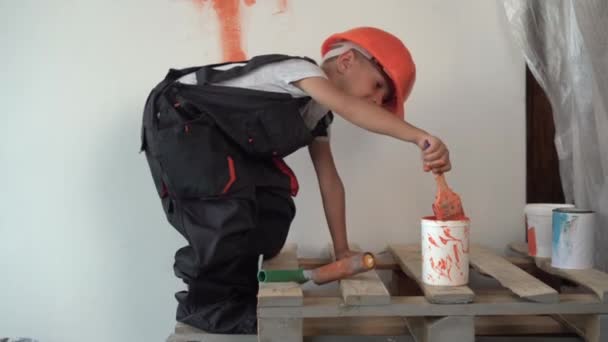 Renovación en el apartamento. Niño feliz pinta la pared con pintura naranja. 4k — Vídeos de Stock