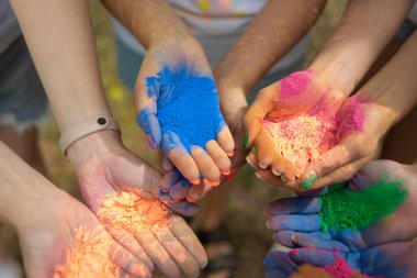 Yazın şehir parkındaki Holi Festivali 'nde avuç içi kuru boya ile insan avuçlarının yakın çekimi. Şehir tatili. Kızlar renkli boyalar atmaya hazır olun. Yüksek kalite fotoğraf