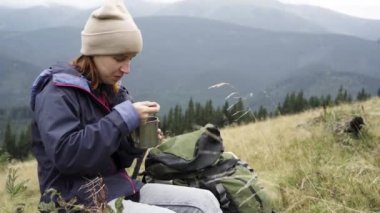 Dağlarda turist kahvaltısı. Kafkasyalı turist oturur ve bir fincandan buğulanmış erişte yer. Dağ sırasının güzel manzarasının tadını çıkarıyorum. Ekose bir gömlekle. Sabah erkenden. Seyahat ve turizm.