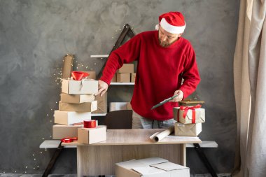 Noel Baba şapkalı bir adam depoda çalışıyor. Online bir mağazadan hediyeler ve mallarla dolu kutuları sayıyor. Küçük işletme bürosu ve Noel indirimi. Girişimci teslimatı hazırlar