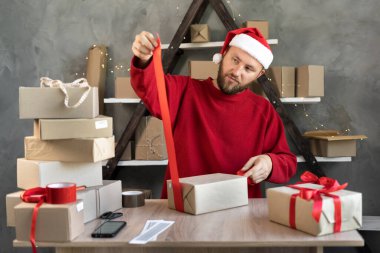 Noel Baba şapkalı bir adam teslimat için depoda Noel hediyeleri hazırlar ve kırmızı kurdele bağlar. Masada karton kutular var ve işadamı eşyalarını topluyor. Yeni yıl indirimi kavramı