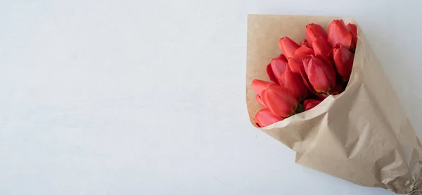 クラフト紙の白い背景に隔離された赤いチューリップの花束 春と夏の背景 母の日バレンタインデー3月8日の誕生日の花と季節の休日 バナー — ストック写真