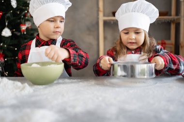 Yakın plan fırıncı kardeşler mutfakta Noel kurabiyeleri hazırlıyorlar. Noel kurabiyesi yapma süreci. Çocuklar hamur işi pişirir. Çocuklar ev yapımı pişirme konsepti pişirir.