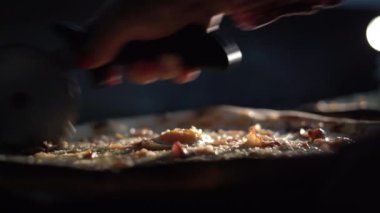 Özel bir bıçakla pizzayı salamla dilimlemek. Bıçak tutan bir el. Sıcak pizza bigudiyle kesilir..