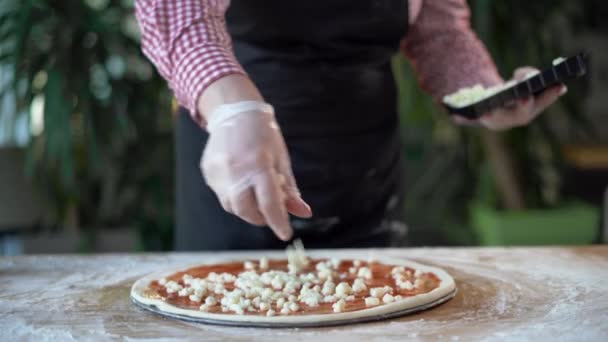 Pizzaiolla pizza séf megszórja mozzarella sajt pizzéria konyhában. Készítsd elő a pizzát. Pepperoni pizzakészítés — Stock videók