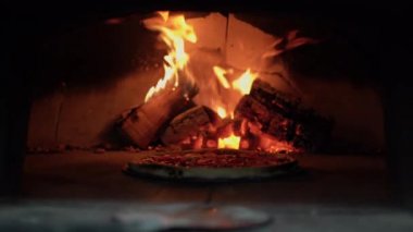 Pizza açık odun fırınında pişirilir. Arka planda yakacak odun yakmak. Geleneksel sıcak pizza margaritası