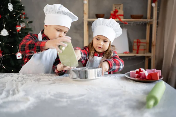 Children brother and sister sift flour for Christmas cookies or gingerbread dough. Childrens culinary blog baking section. Little bakers — Stock Photo, Image