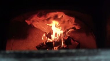 Tuğla fırınında odun yakmak pizza yapmak için ateş yakmak. Ocakta odun yanıyor..