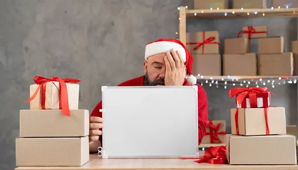 A man small business owner of an online store, a manager, a working entrepreneur in a santa claus hat. Bearded santa in depression. Big New Year Sale — Stock Photo, Image