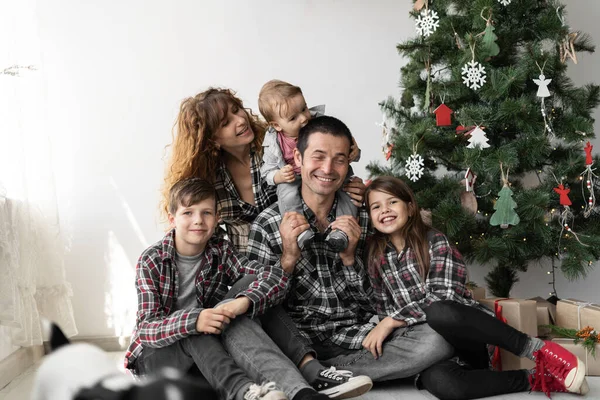 Portret dużej białej rodziny z trójką dzieci na Boże Narodzenie z prezentami siedzącymi na podłodze domu w salonie. — Zdjęcie stockowe