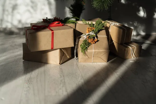 Caixas de presente no quarto em casa no chão debaixo da árvore. Embalagem de caixa de artesanato. Véspera de Natal. Decoração de surpresas caseiras para a família. — Fotografia de Stock
