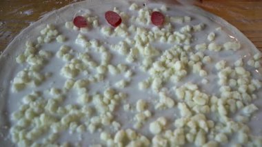 Şef pizza pişirir. Salam sosisinin arka planında hamurda malzemeler var. Yemek tarifi kitabı ve menüsü..